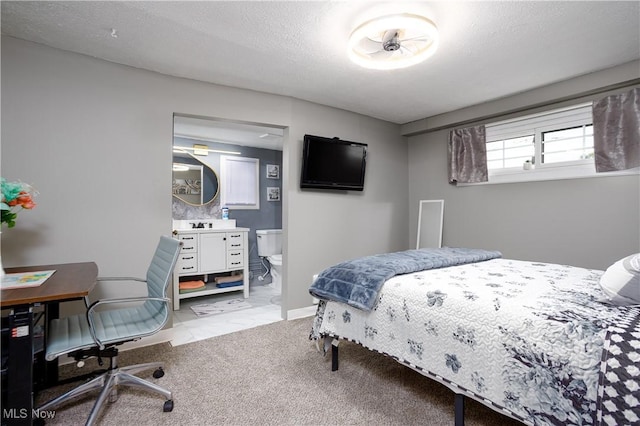 bedroom with light carpet, a textured ceiling, baseboards, and ensuite bathroom