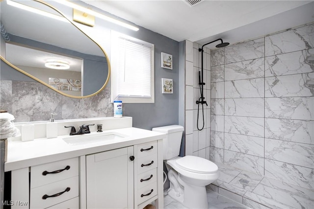 full bath featuring toilet, marble finish floor, tiled shower, and vanity