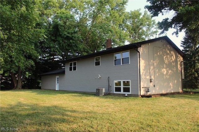 rear view of house featuring central AC and a yard