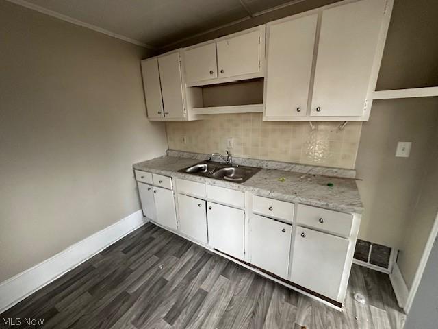 kitchen featuring sink, white cabinets, dark hardwood / wood-style flooring, decorative backsplash, and crown molding