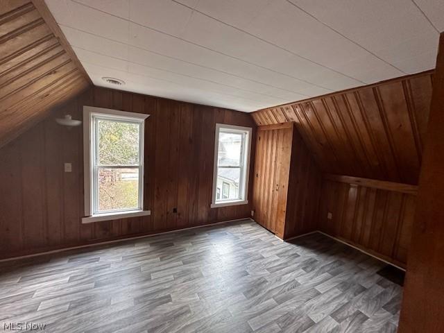 additional living space featuring lofted ceiling, hardwood / wood-style floors, and wood walls