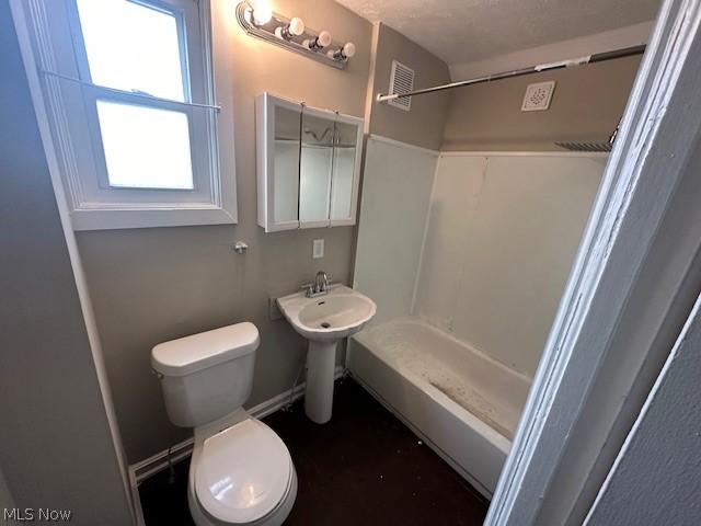 bathroom with toilet, sink, a textured ceiling, and a shower