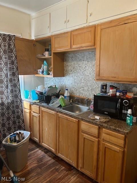 kitchen with backsplash, sink, dark stone counters, and dark hardwood / wood-style floors