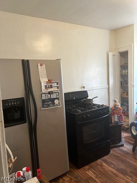 kitchen featuring gas stove, stainless steel fridge with ice dispenser, and dark wood-type flooring