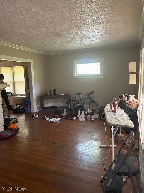 miscellaneous room featuring dark wood-type flooring, a textured ceiling, and ornamental molding