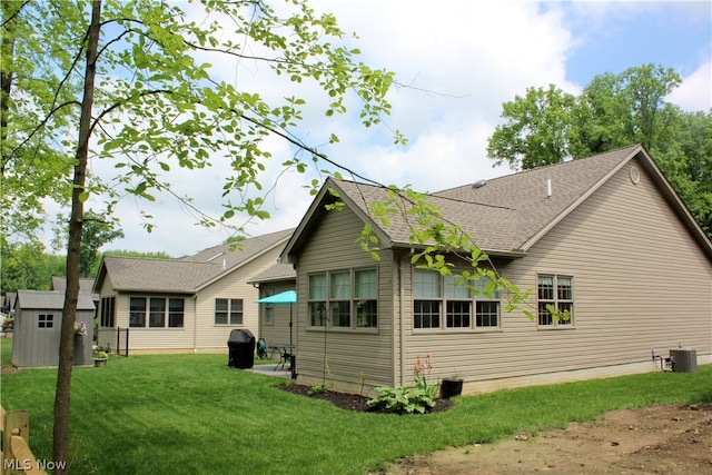 back of property with central AC and a lawn