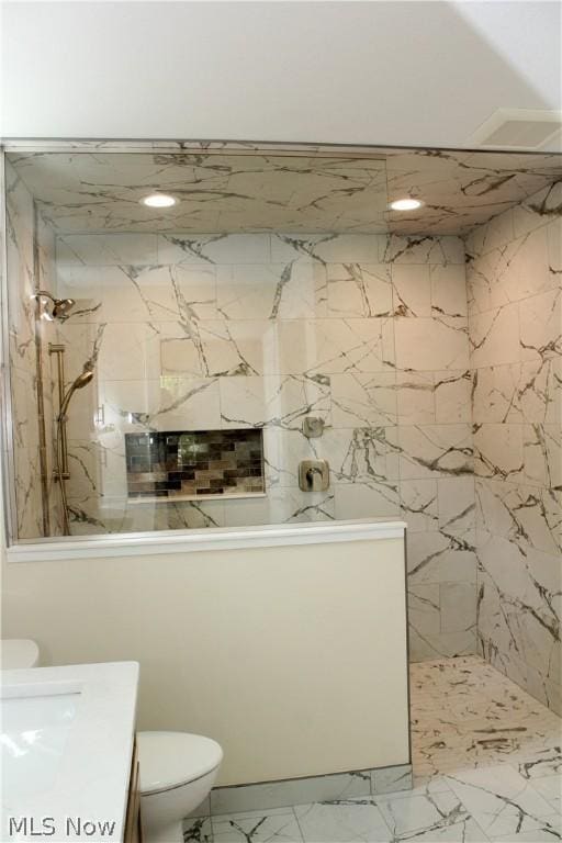 bathroom featuring vanity, tiled shower, and toilet