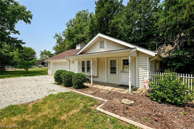 view of front of home with a garage, covered porch, and a front lawn