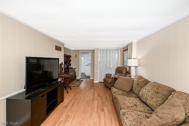 living area with light wood-type flooring and ornamental molding