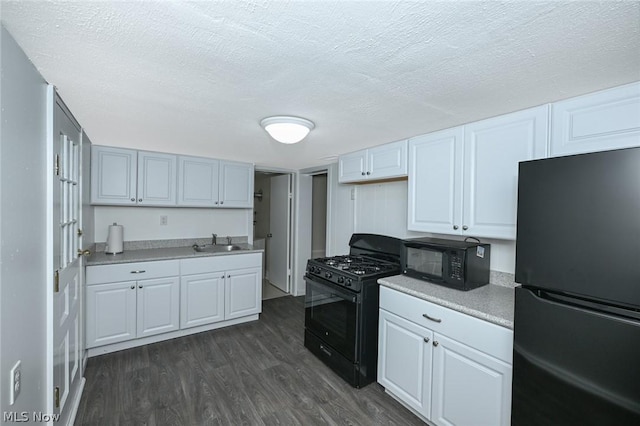 kitchen with a sink, black appliances, white cabinets, dark wood-type flooring, and a textured ceiling