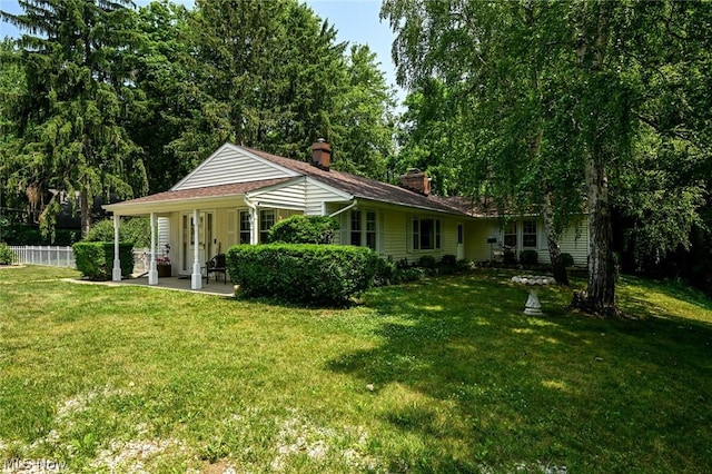 exterior space with a lawn, a chimney, a patio, and fence