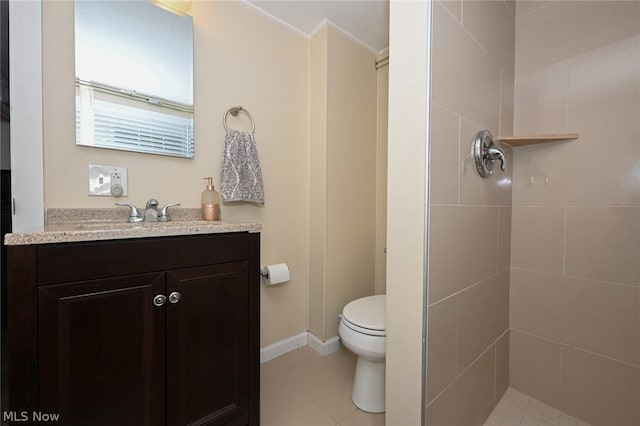 full bathroom with vanity, toilet, baseboards, and tiled shower