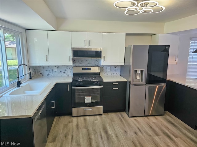 kitchen with white cabinets, sink, light hardwood / wood-style flooring, light stone countertops, and stainless steel appliances