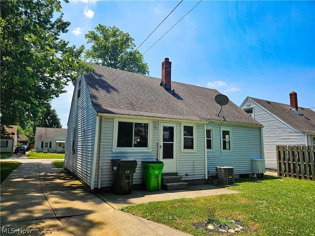 back of property featuring a lawn and central air condition unit