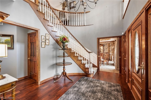 carpeted foyer entrance with a towering ceiling and a chandelier