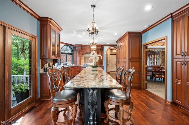 kitchen with dark hardwood / wood-style floors, a center island, light stone counters, and a notable chandelier