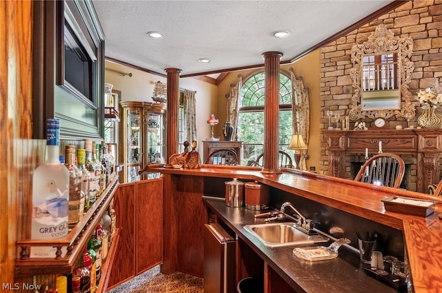 bar with a textured ceiling, ornamental molding, stainless steel dishwasher, sink, and vaulted ceiling