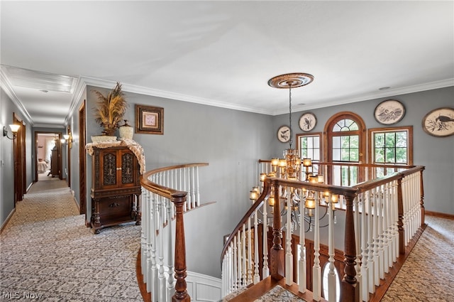 corridor with a notable chandelier, carpet, and crown molding