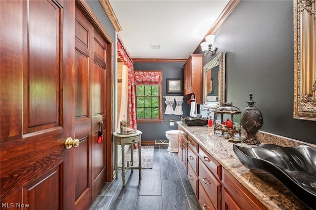 bathroom with tile floors, double sink vanity, crown molding, and toilet