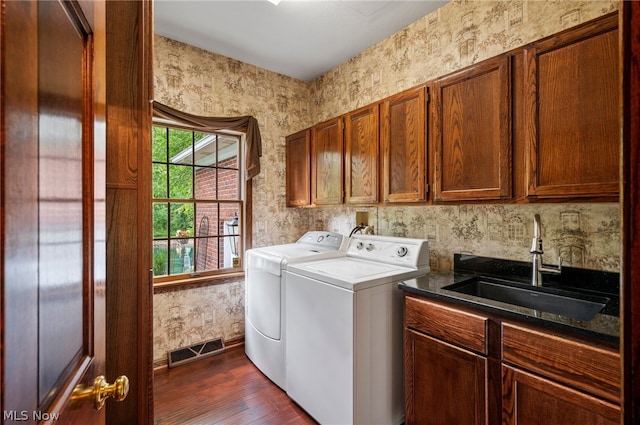 clothes washing area featuring cabinets, washing machine and clothes dryer, dark hardwood / wood-style flooring, hookup for a washing machine, and sink