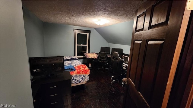 bedroom with dark wood-type flooring, vaulted ceiling, and a textured ceiling