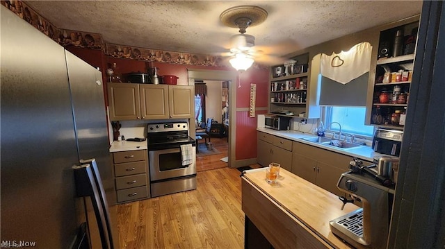 kitchen with sink, light hardwood / wood-style flooring, ceiling fan, stainless steel appliances, and a textured ceiling