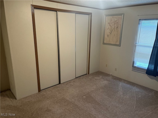 unfurnished bedroom with light colored carpet and a textured ceiling