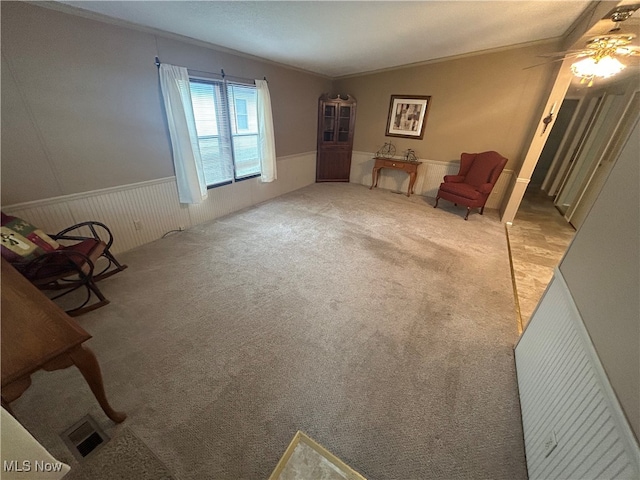 living area featuring light carpet, crown molding, and ceiling fan