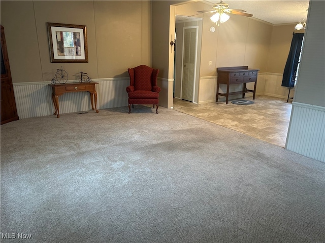 living area featuring a textured ceiling, ceiling fan, light colored carpet, and crown molding