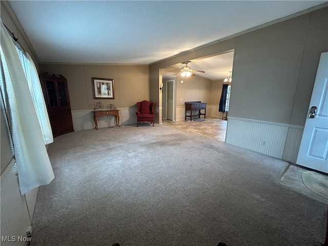 unfurnished living room with ceiling fan, light colored carpet, lofted ceiling, and crown molding