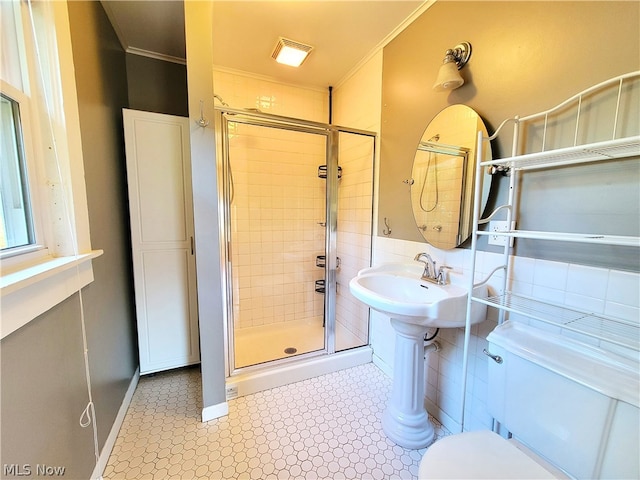 bathroom with a shower with shower door, tile flooring, ornamental molding, and toilet