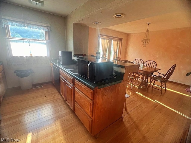 kitchen featuring kitchen peninsula, light wood-type flooring, a wealth of natural light, dishwashing machine, and sink