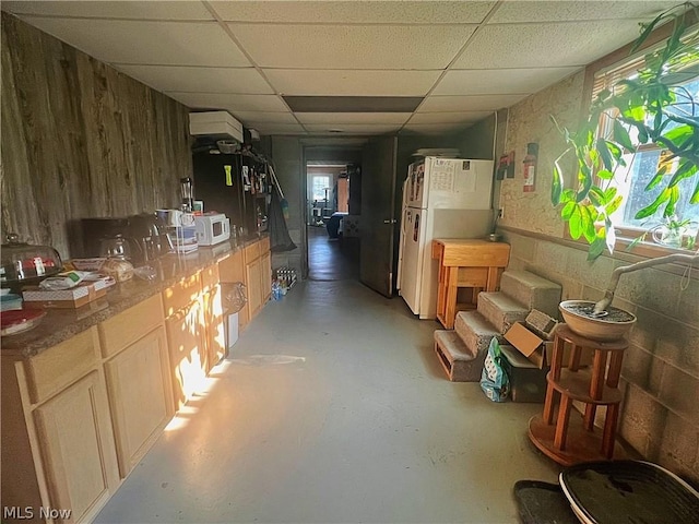 interior space with a paneled ceiling and white fridge