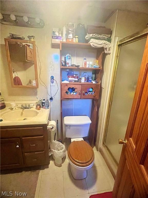 bathroom featuring tile patterned floors, toilet, vanity, and walk in shower