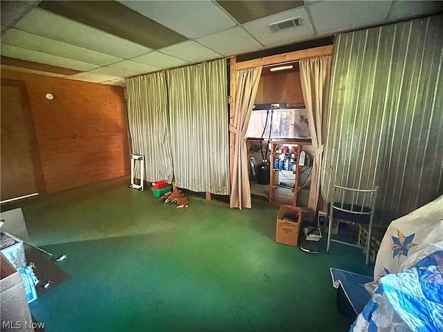 miscellaneous room with wooden walls, a drop ceiling, and carpet