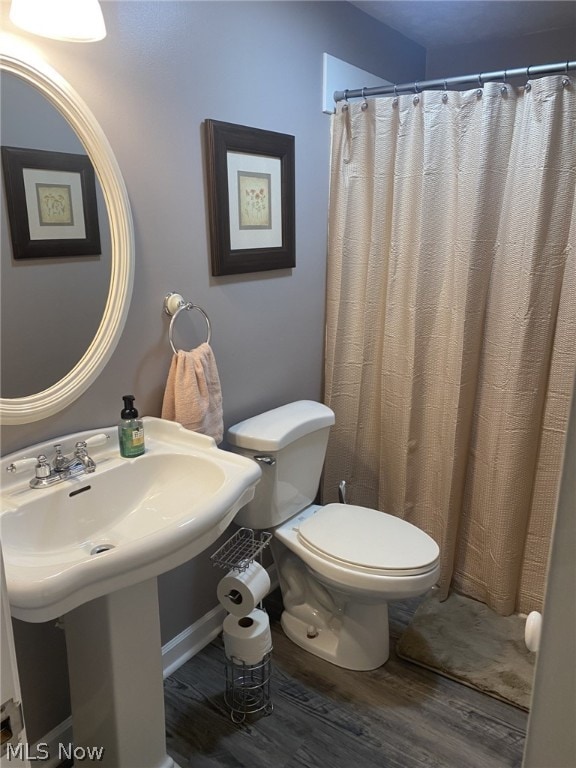 bathroom featuring hardwood / wood-style floors, toilet, and curtained shower