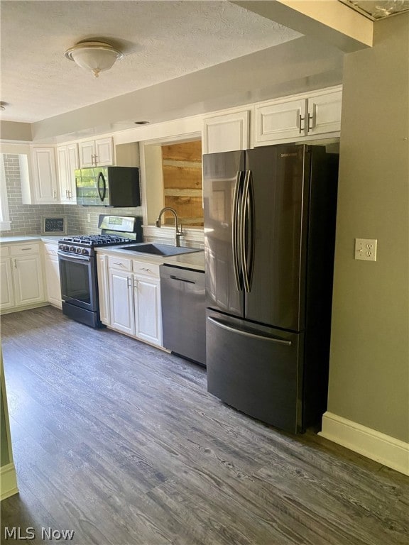 kitchen featuring hardwood / wood-style floors, sink, appliances with stainless steel finishes, tasteful backsplash, and white cabinetry