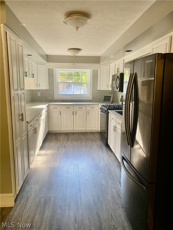 kitchen with backsplash, dark hardwood / wood-style flooring, white cabinetry, and stainless steel appliances