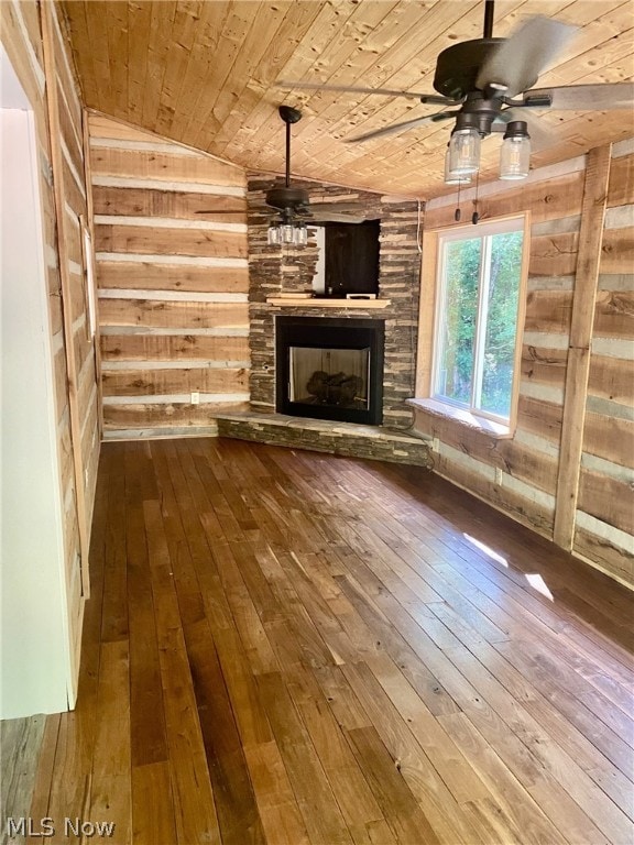 unfurnished living room featuring wood ceiling, vaulted ceiling, wood-type flooring, a fireplace, and wood walls