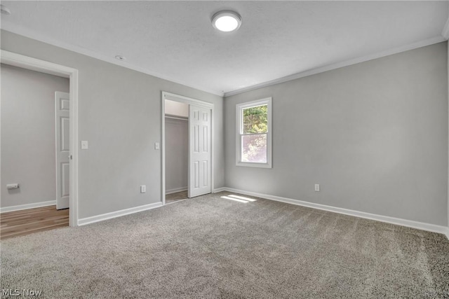 unfurnished bedroom with carpet, a closet, and ornamental molding