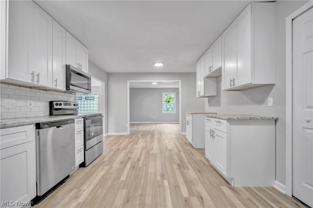 kitchen with white cabinetry, light stone counters, and appliances with stainless steel finishes