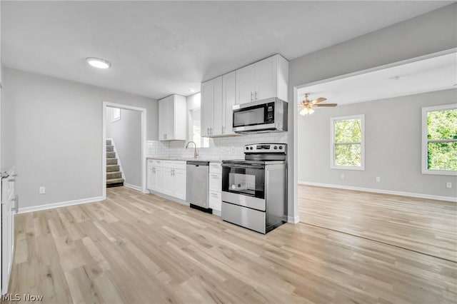 kitchen featuring backsplash, white cabinetry, stainless steel appliances, and light hardwood / wood-style floors