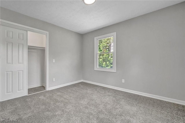 unfurnished bedroom featuring carpet flooring, a textured ceiling, and a closet