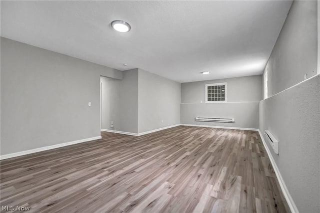 unfurnished room with hardwood / wood-style flooring and baseboard heating