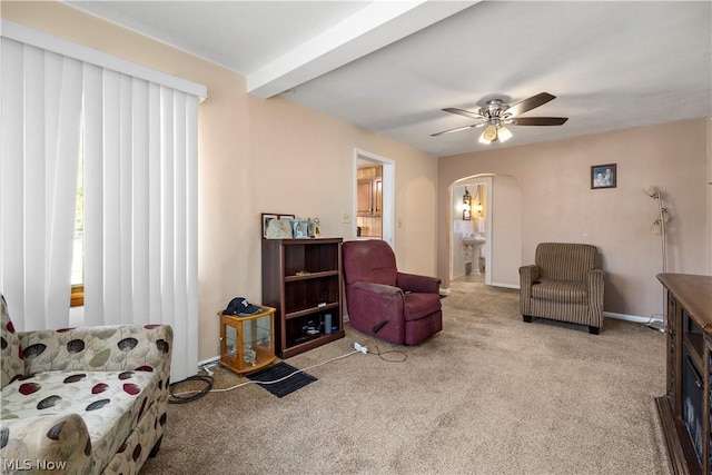 carpeted living room featuring ceiling fan and beamed ceiling