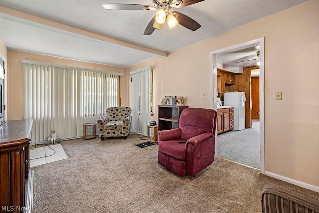 sitting room featuring ceiling fan, carpet, and beam ceiling