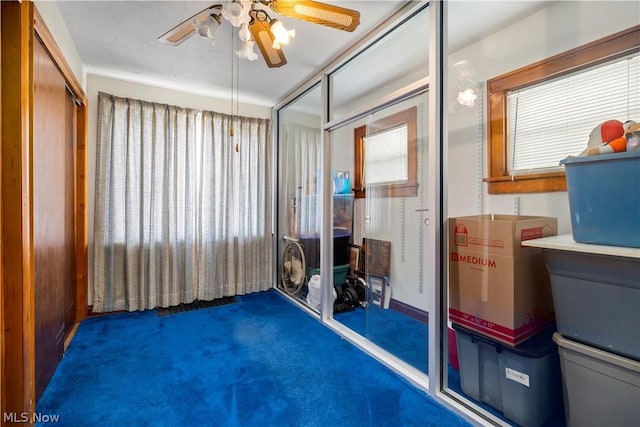 interior space with dark carpet and ceiling fan