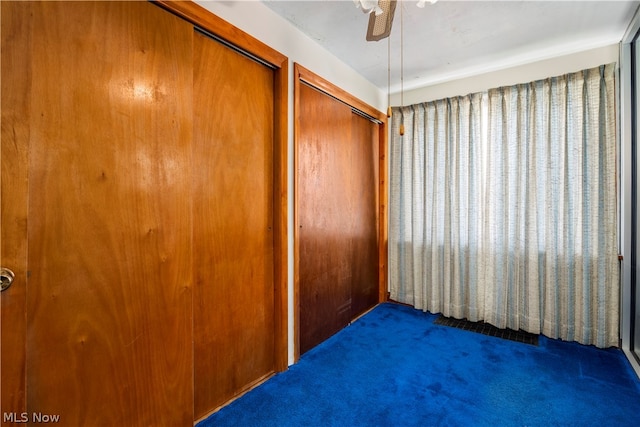 unfurnished bedroom featuring ceiling fan and dark carpet