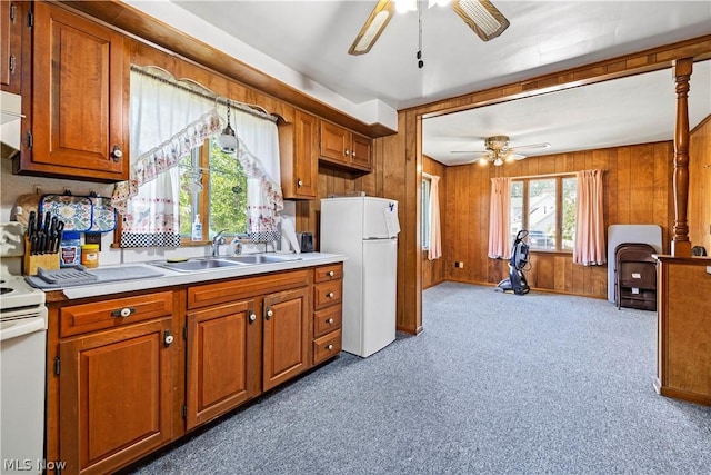 kitchen featuring sink, white appliances, ceiling fan, dark carpet, and wood walls