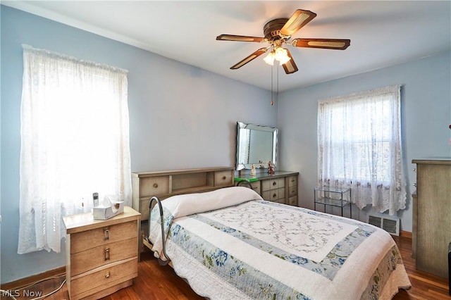 bedroom featuring ceiling fan, dark hardwood / wood-style flooring, and multiple windows